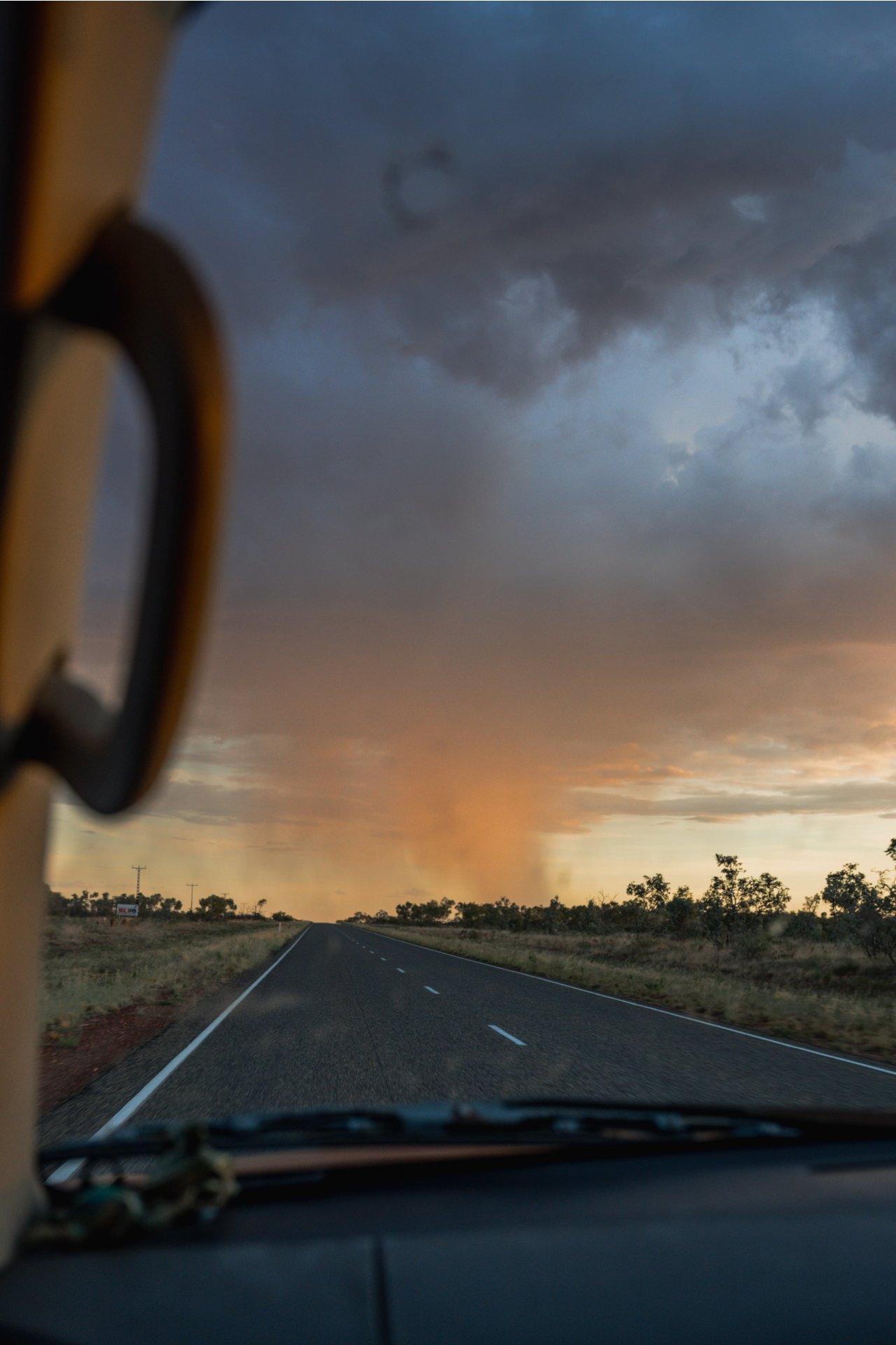 Road on a highway with a dramatic sky over a flat landscape.