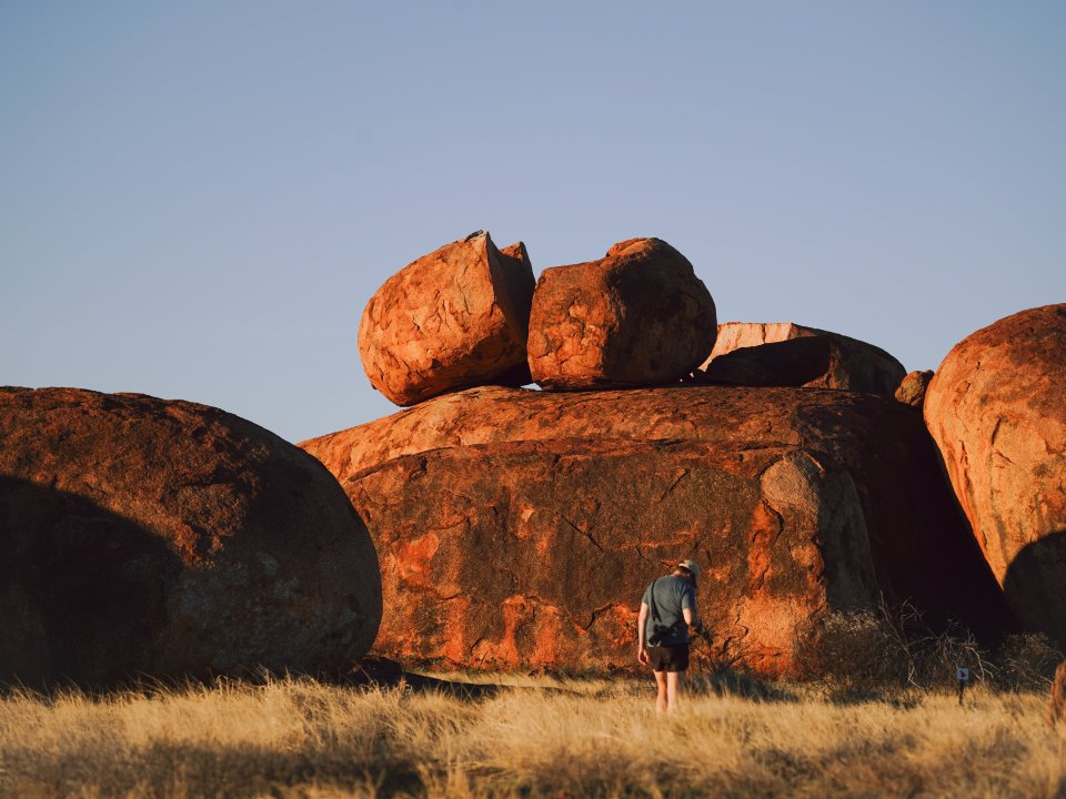 Person standing among large granite boulders in a desert landscape.