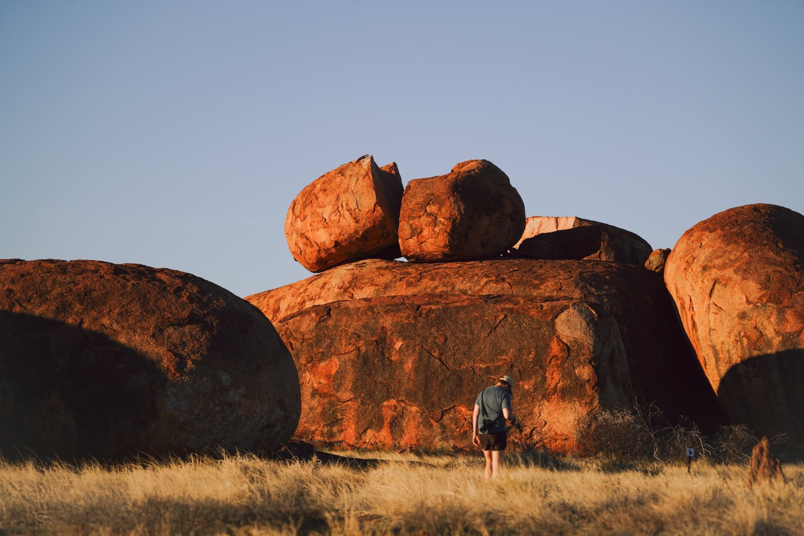 Person standing among large granite boulders in a desert landscape.