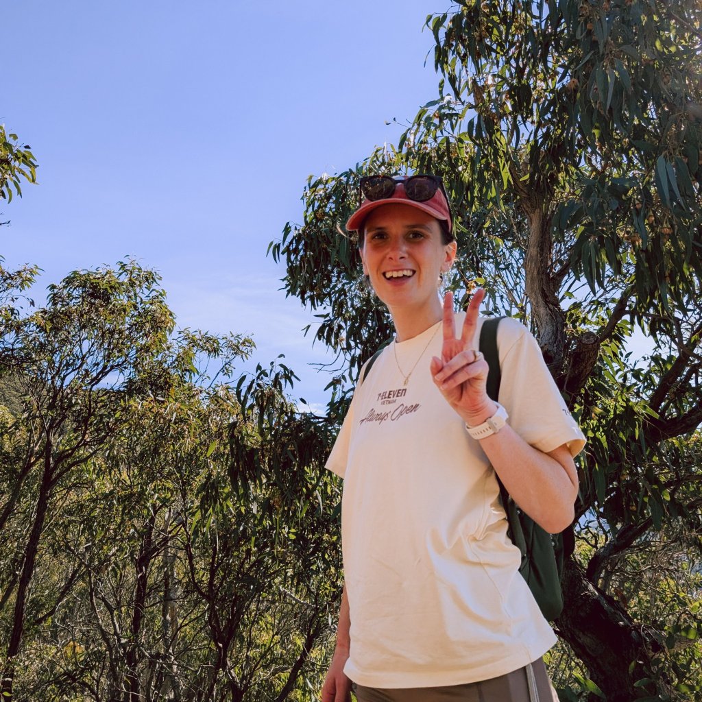 Woman smiling outdoors in a lush, green forest setting.