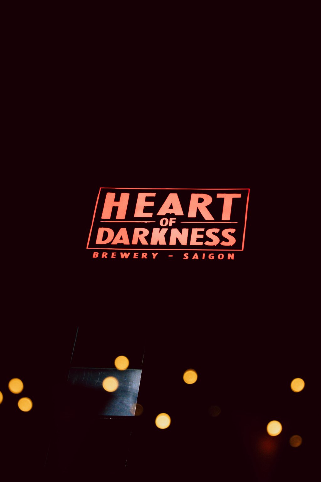 Heart of Darkness beer sign glowing on a dark street at night.