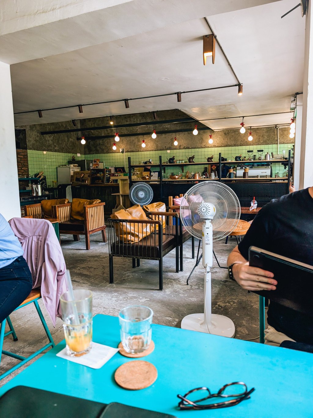 Interior view of a cafe setting with wooden furniture and decorative fans in Ho Chi Minh City.