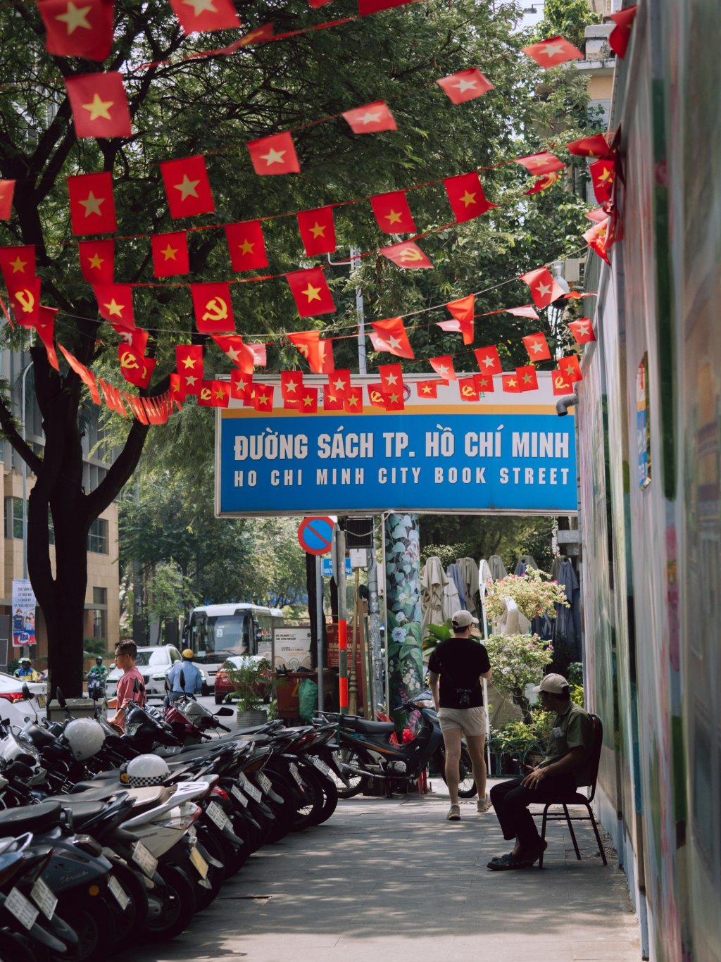Street scene in Ho Chi Minh City featuring red Vietnamese flags strung across a busy street.