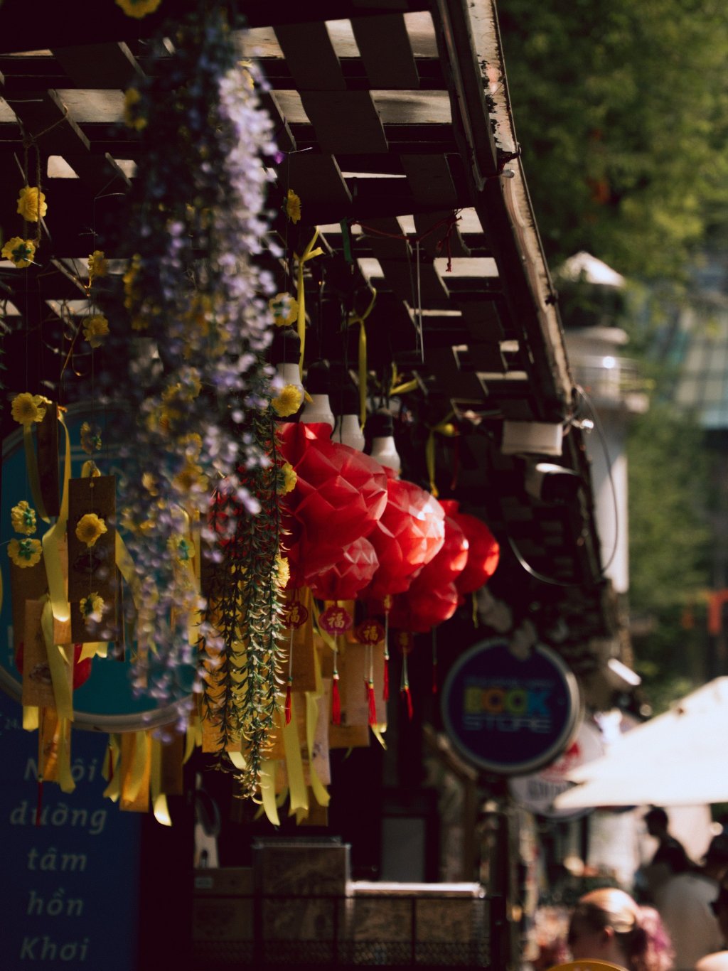 Colorful hanging decorations and market stalls lining a street in Ho Chi Minh City.
