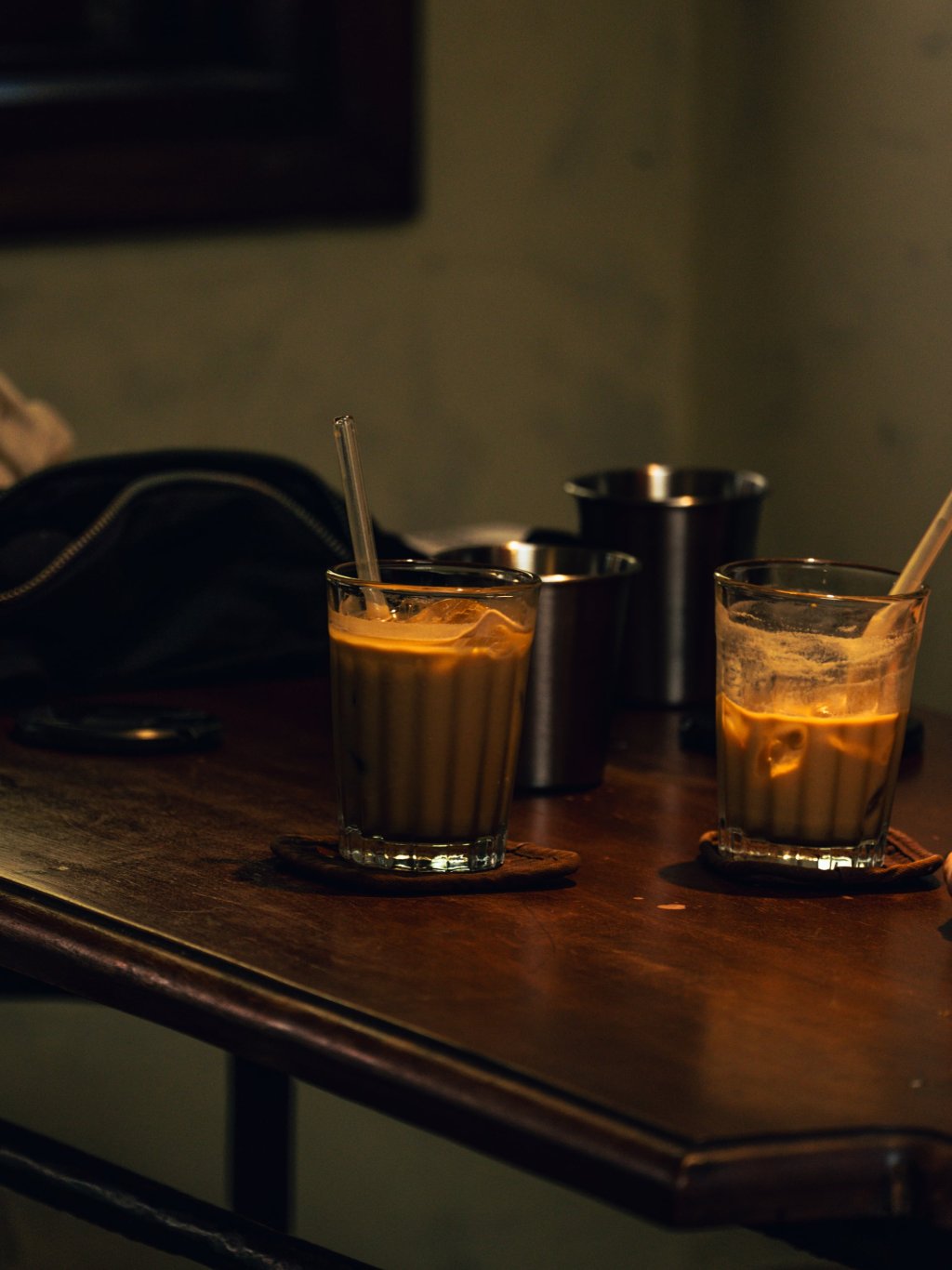 Two glasses of iced coffee sitting on a dark wooden table in Ho Chi Minh City.