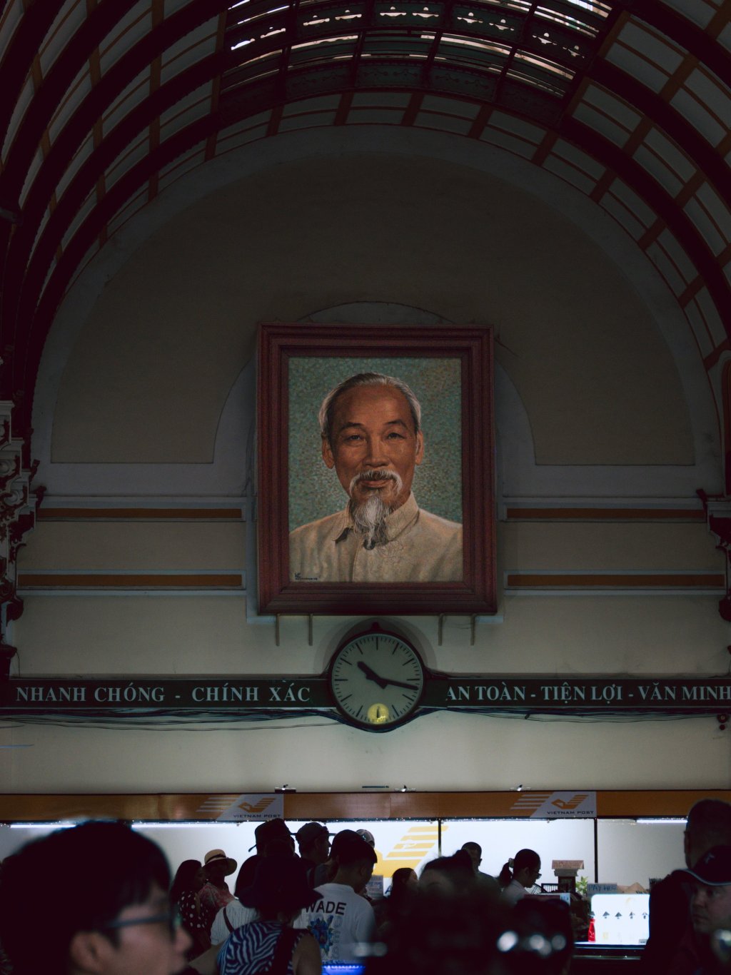 Portrait and clock above the arched hall inside Saigon Central Post Office.