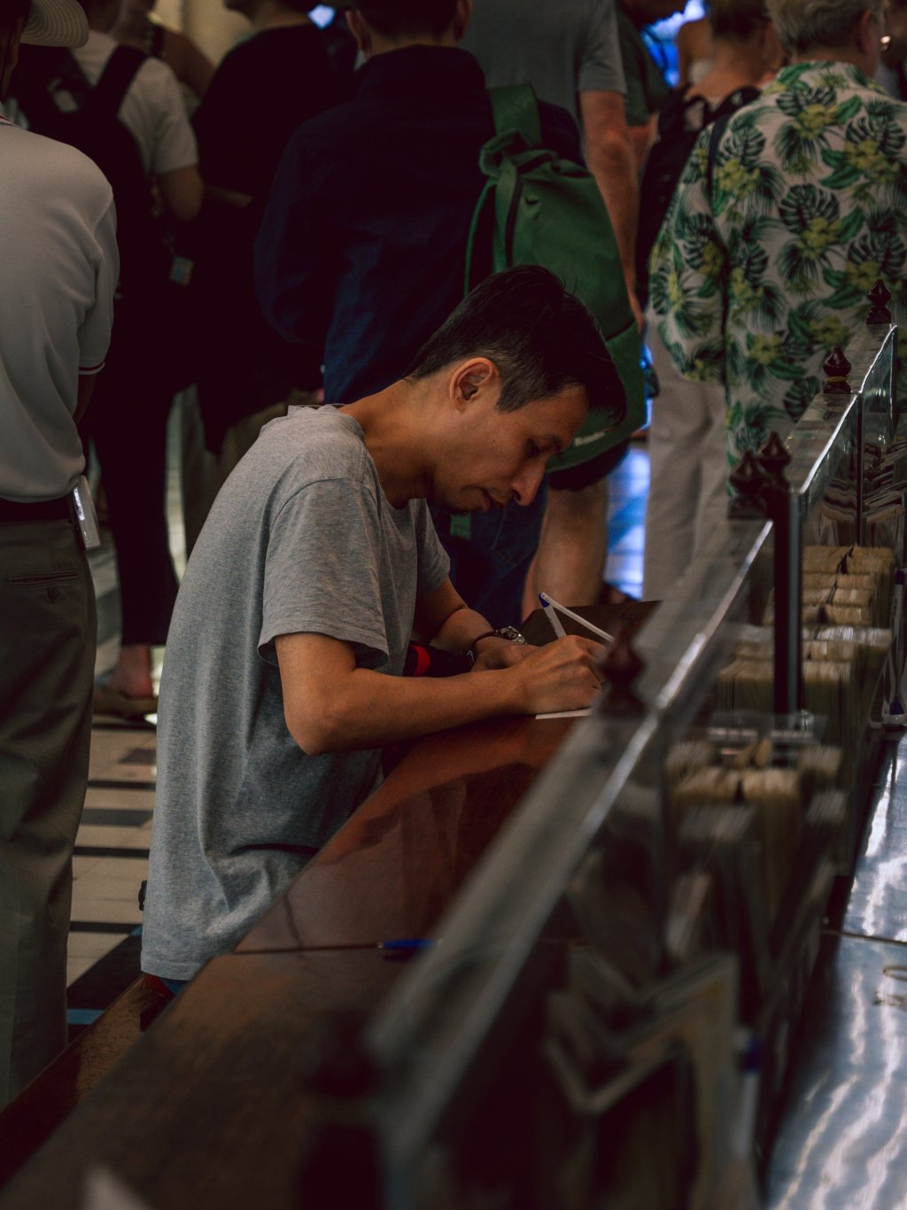 Person writing at a counter inside Saigon Central Post Office.