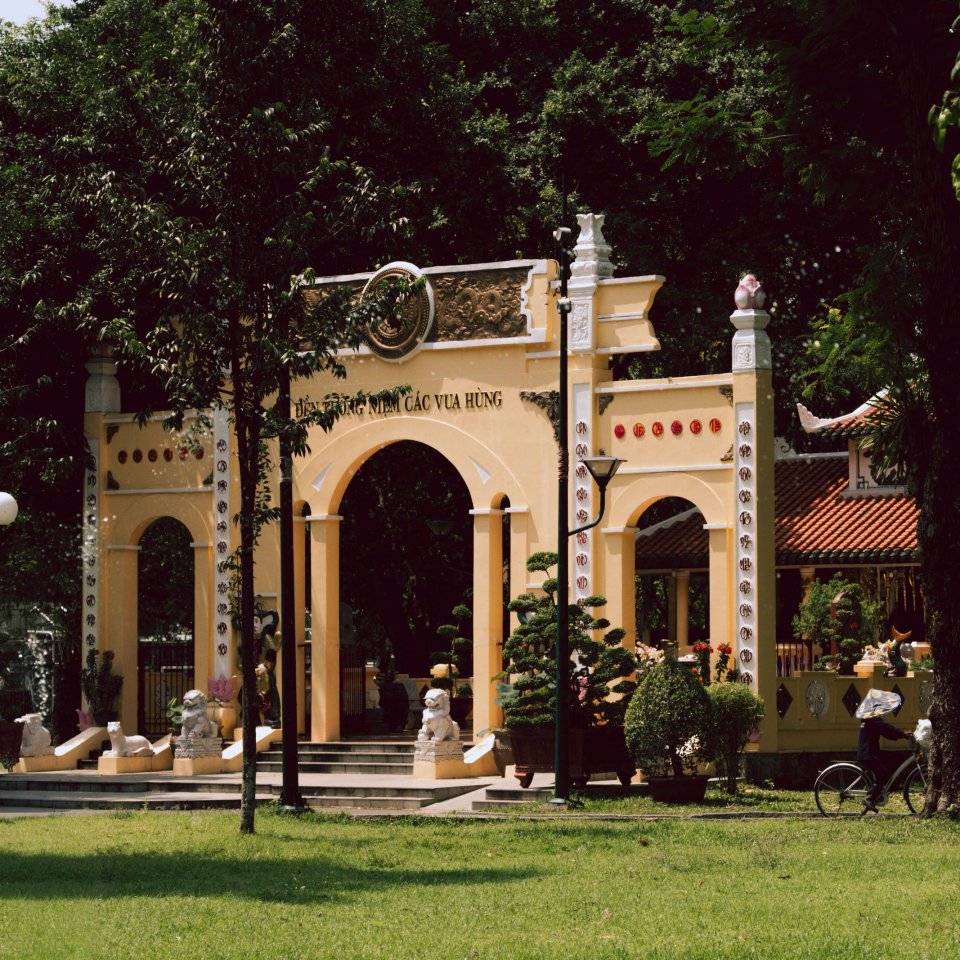Architectural facade with arched entrances and greenery in a courtyard setting.