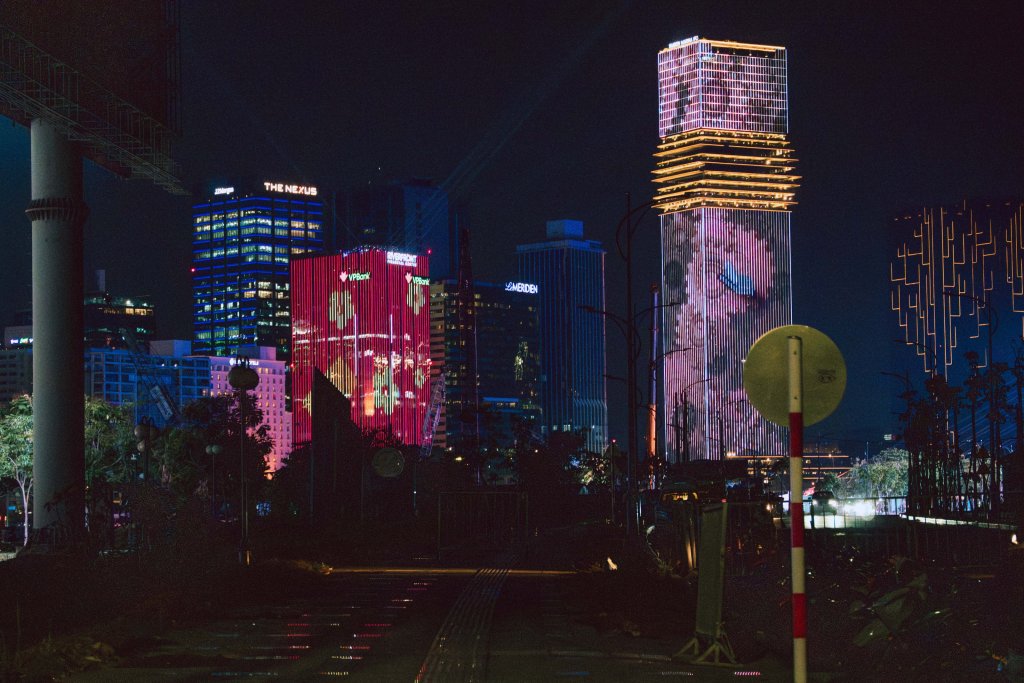 Night view of city skyline with illuminated buildings and tall structures.