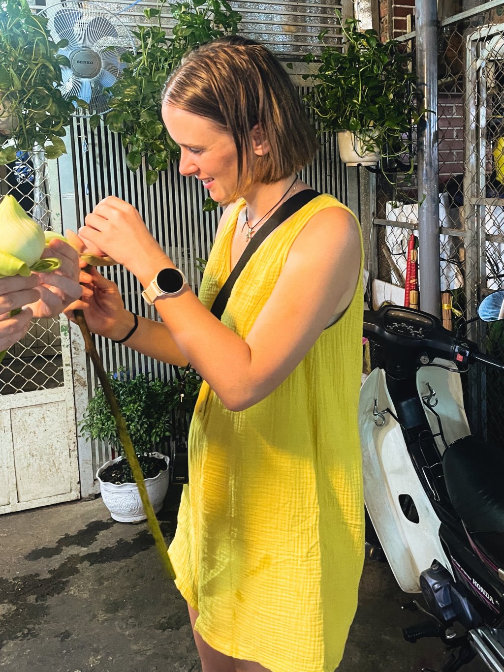 Woman tending to plants on a balcony or outdoor area.