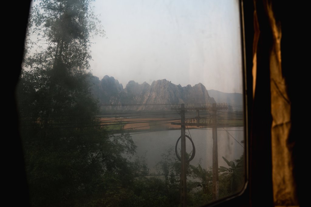 Rice fields and karst scenery seen through the window of a Vietnamese train cabin.