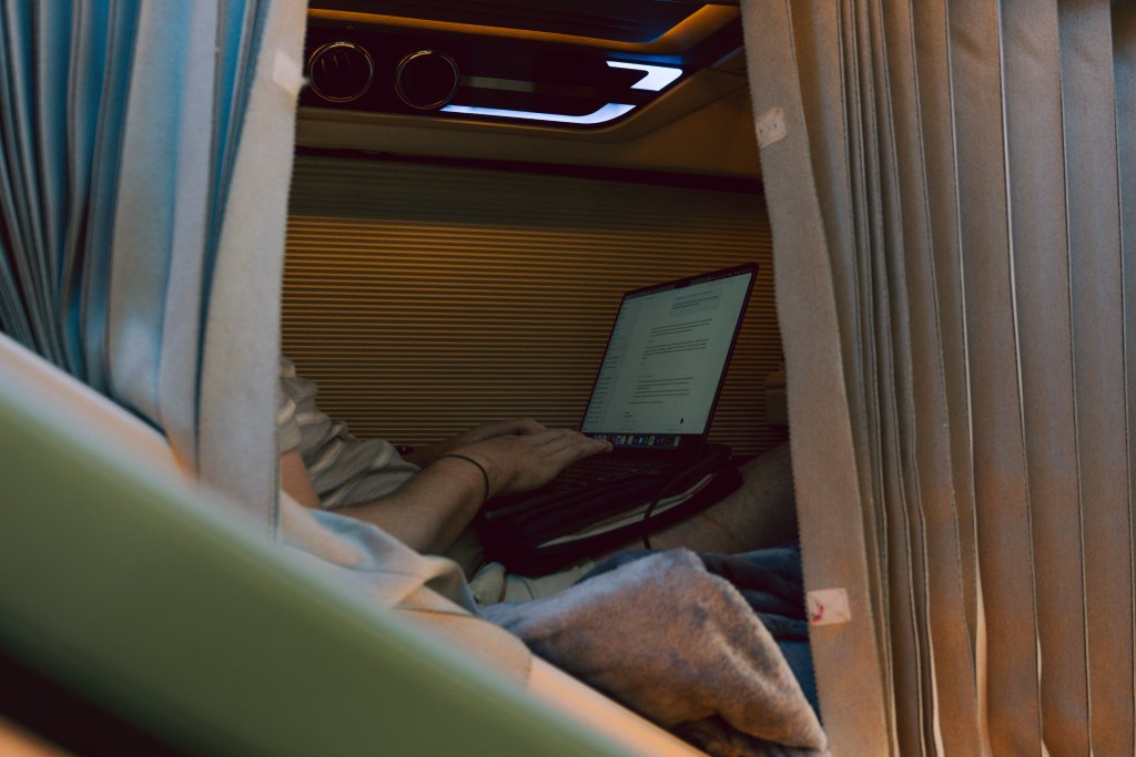 A private sleeper bus pod with blue bedding and curtains inside a Vietnam sleeper bus.
