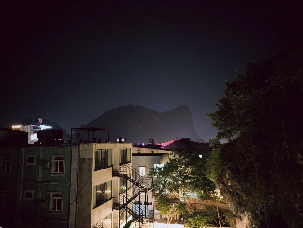 Night view of buildings and hills in a city setting.