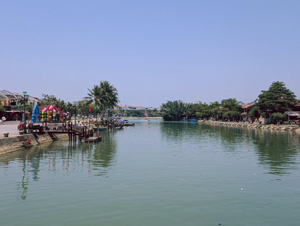 View of a calm body of water with wooden structures and trees along the bank.