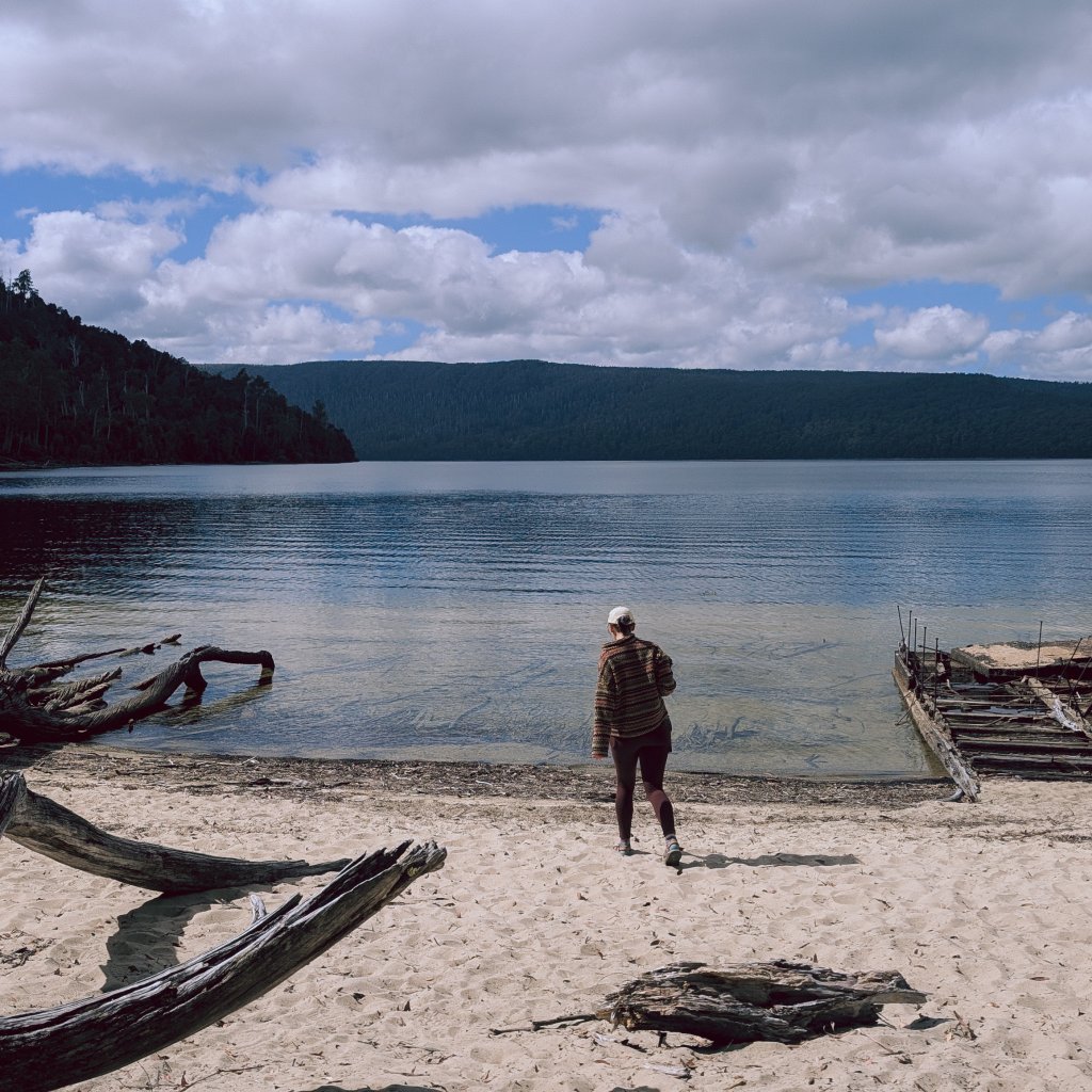 Hannah walking on a sandy beach at the edge of Lake St Clair
