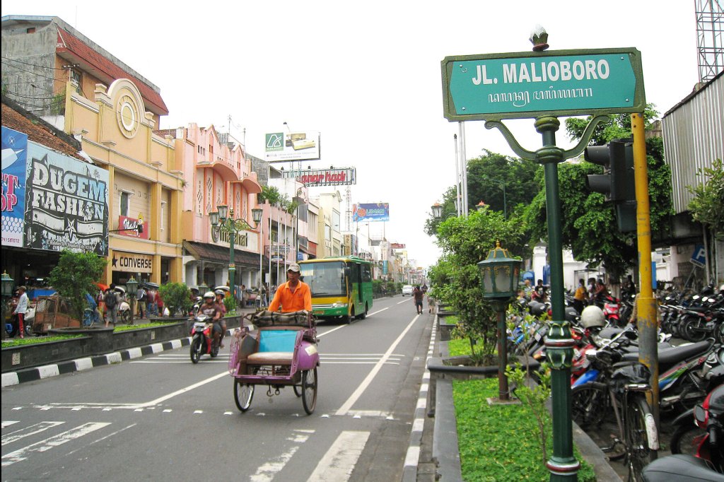 Malioboro Street in Yogyakarta with traffic, shops and a becak.