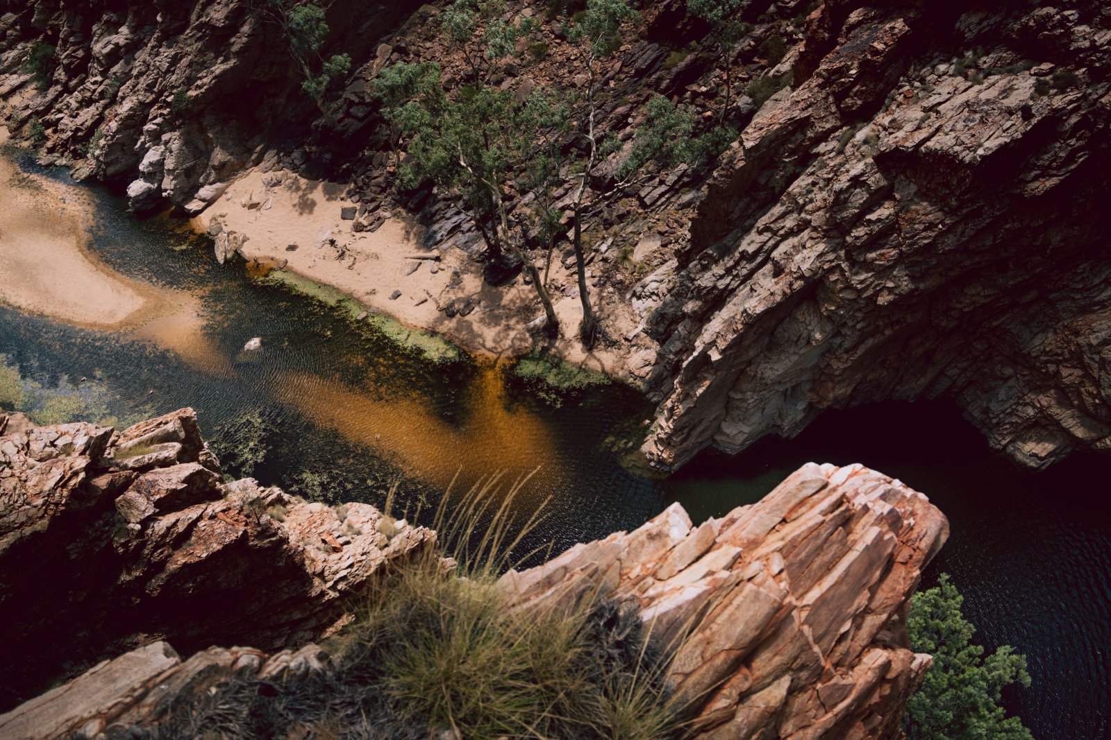 Aerial view of a Central Australian gorge with dark water and rocky terrain