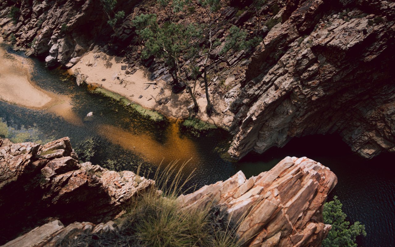 Aerial view of a Central Australian gorge with dark water and rocky terrain